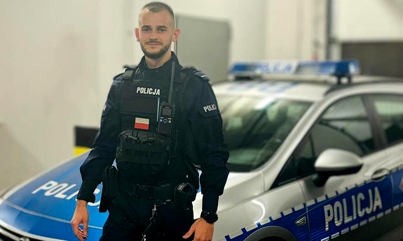 Policjant stoi przy radiowozie policyjnym