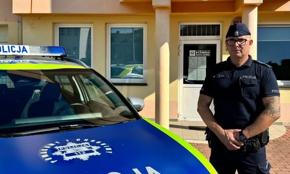 policjant stoi przy radiowozie