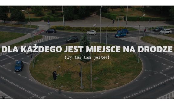 zdjęcie ronda, na którym widać jadące samochody a na środku biały napis: Dla każdego jest miejsce na drodze (Ty też tam jesteś)