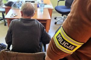 Zatrzymany mężczyzna siedzi na krześle podczas przesłuchania.