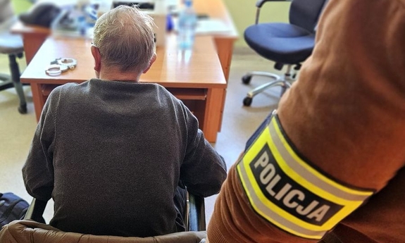 Zatrzymany mężczyzna siedzi na krześle podczas przesłuchania.