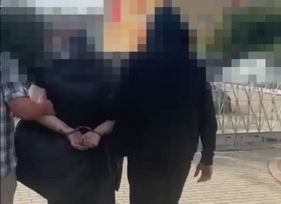 Policjanci prowadzą zatrzymaną. Obraz jest zablurowany.