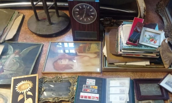 Leżące na podłodze obrazy, album ze znaczkami, drewniany zegar.