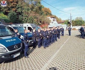 Policyjne radiowozy i stojący przy nich policjanci.
