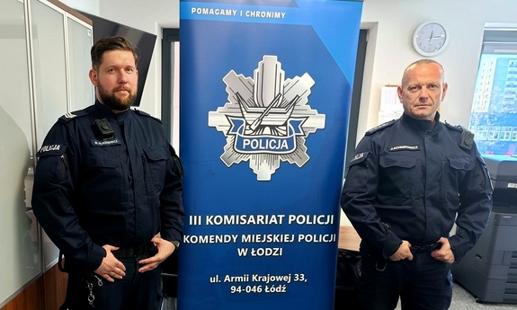 Dzielnicowi, którzy uratowali seniora stoją w pomieszczeniu komisariatu obok roll-upu z logiem łódzkiej Policji i napisem III Komisariat Policji Komendy Miejskiej Policji w Łodzi ul. Armii Krajowej 33, 94-046 Łodź