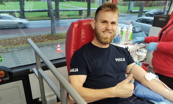 policjant oddaje krew i pokazuje kciuka w górę