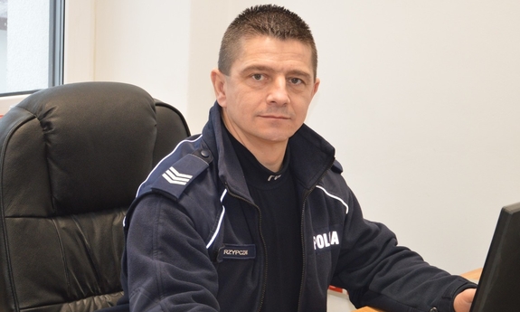 Dzielnicowy Piotr Skrzypczak siedzi przy biurku.