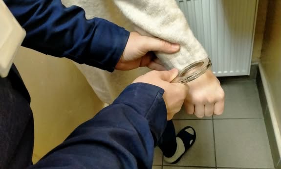 policjant skuwa kajdankami zatrzymanego.