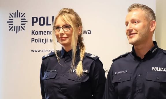 policjantka i policjant pozują do zdjęcia i uśmiechają się.