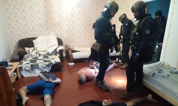 Oddział policjantów antyterrorystycznych, w trakcie zatrzymania trzech mężczyzn, którzy leżą na podłodze zakuci w kajdanki.