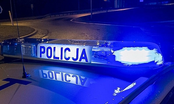 Pora nocna. Belka policyjnego radiowozu z napisem Policja.