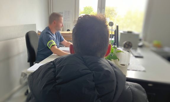 dwaj mężczyźni siedzą za stołem.