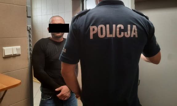 policjant stoi z zatrzymanym.