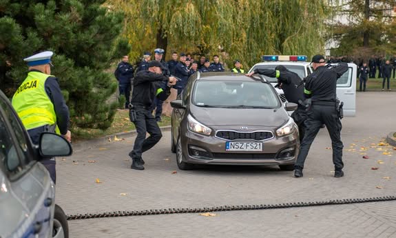 samochód stoi na drodze, dookoła stoją policjanci.