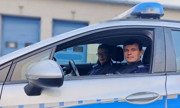 dwóch policjantów siedzi w radiowozie.