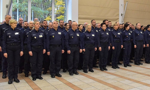 Grupa policjantów stojąca kilku szeregach na auli.