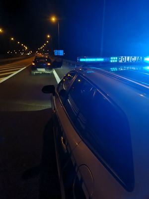 Pora nocna. Policyjny radiowóz, przed nim pojazd bmw.