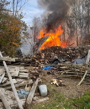palący się budynek, dookoła pocięte drewno.