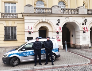 policjanci stoją przy radiowozie.