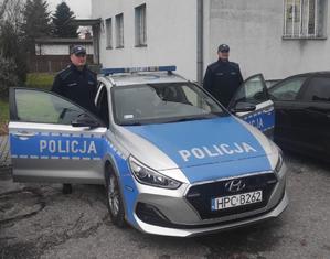 policjanci stoją przy radiowozie.