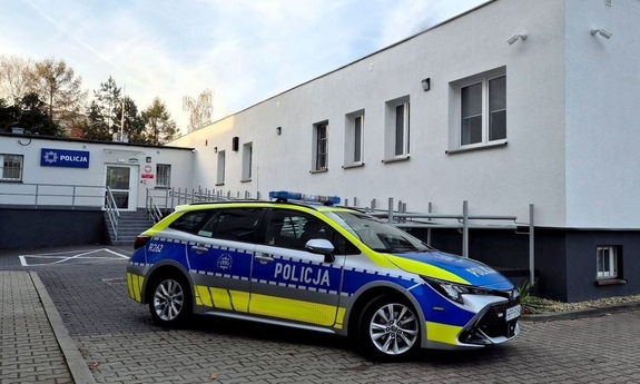 Radiowóz policyjny stoi przed nowym budynkiem komisariatu.