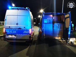 Radiowóz policyjny stoi na drodze obok zatrzymanego busa.