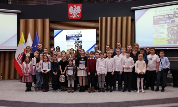 Uczestnicy konferencji pozują do zdjęcia na scenie auli Świętokrzyskiego Urzędu Wojewódzkiego w Kielcach.