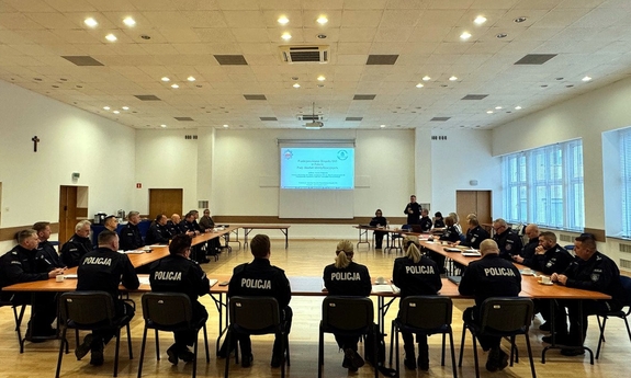 Na zdjęciu umundurowani policjanci siedzą na sali, słuchając prezentacji.