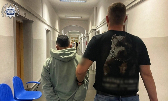 Policjant z zatrzymanym w kajdankach.