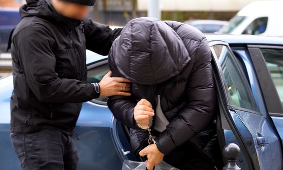 policjant idzie z zatrzymanym.