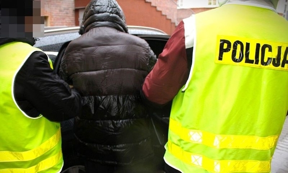 Dwaj policjanci prowadza zatrzymanego.