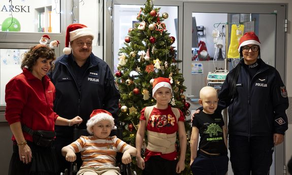 policjanci z dziećmi stoją obok choinki.