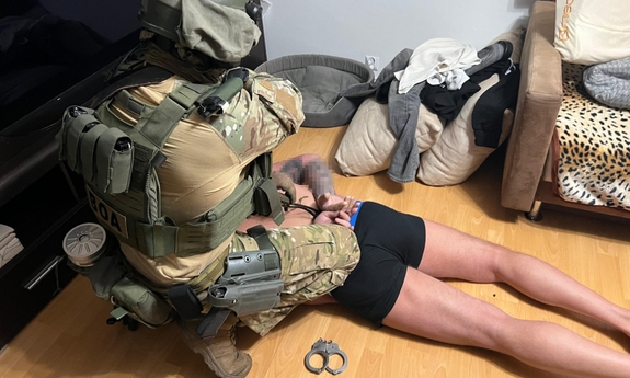 Policjant obezwładnia mężczyznę leżącego na podłodze.