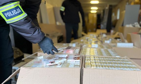 policjant przeszukuje kartony z papierosami.