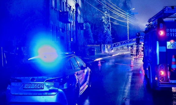 Policyjny, oznakowany radiowóz oraz pojazd Państwowej Straży Pożarnej przy kamienicy.