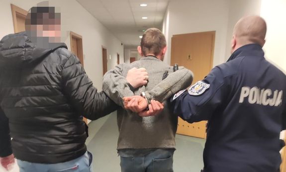 policjanci idą z zatrzymanym.