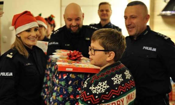 Grupa policjantów wręczająca prezent chłopcu.