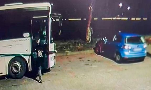 Mężczyzna kopie drzwi w zaparkowanym autobusie.