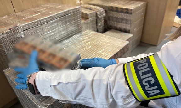 Policjant zabezpiecza paczki papierosów.