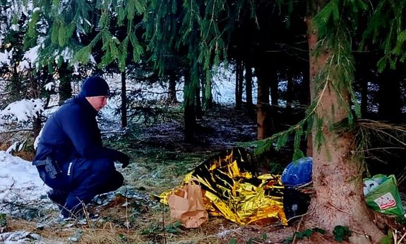las. policjant przykrył mężczyznę kocem.