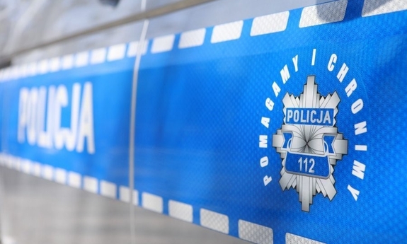 Napis Policja i logo Pomagamy i chronimy na drzwiach radiowozu policyjnego.