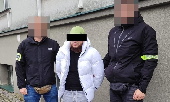 Dwaj funkcjonariusze z zatrzymanym w kajdankach.