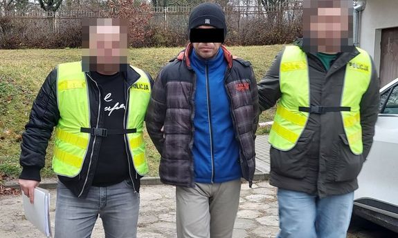 policjanci idą z zatrzymanym.
