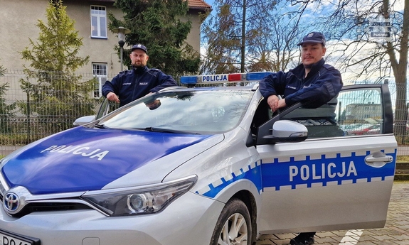 Dwaj policjanci przy radiowozie.