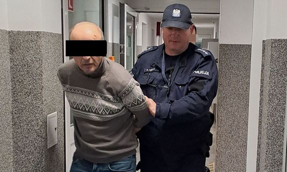 policjant idzie z zatrzymanym.