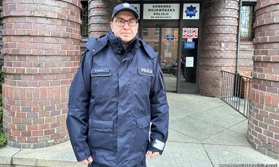 Policjant, który uratował stoi przed budynkiem Komendy Wojewódzkiej Policji.