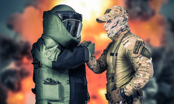 grafika, policjant z boa podaje rękę policjantowi w specjalnym stroju do rozbrajania bomb.