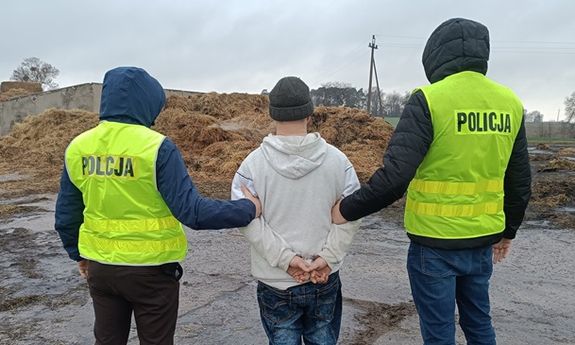 policjanci stoją z zatrzymanym.