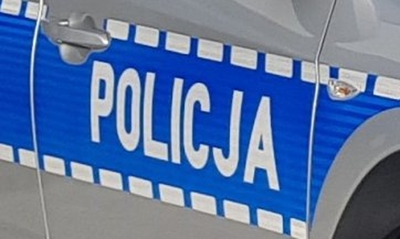 Fragment radiowozu policyjnego. Napis Policja na drzwiach radiowozu.