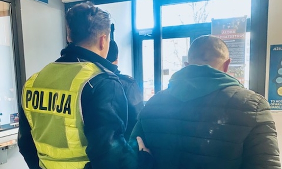 Funkcjonariusz prowadzi zatrzymanego.